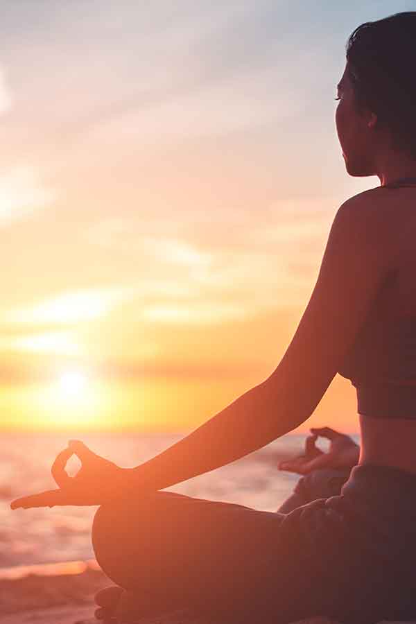 Eine Frau sitzt am Strand und lässt sich von der Sonne anstrahlen